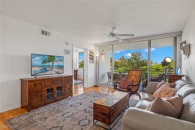 living room featuring floor to ceiling windows, ceiling fan, and light hardwood / wood-style flooring