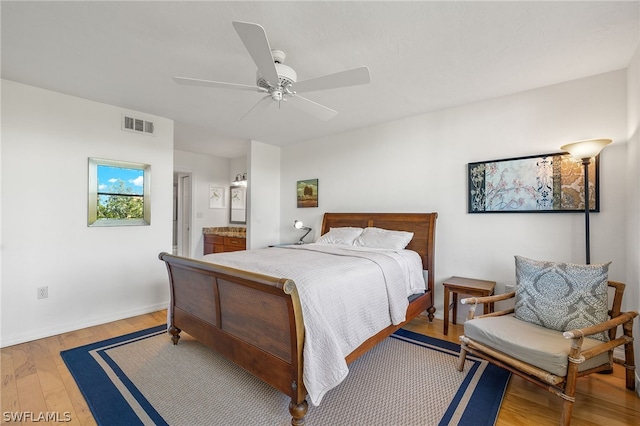 bedroom with ensuite bathroom, ceiling fan, and hardwood / wood-style flooring