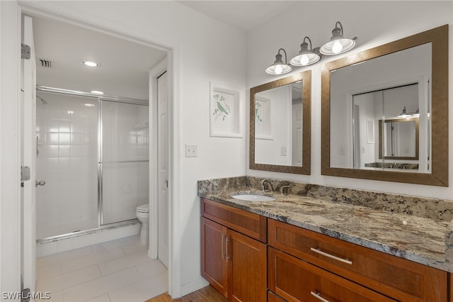 bathroom with tile patterned floors, vanity, toilet, and a shower with shower door