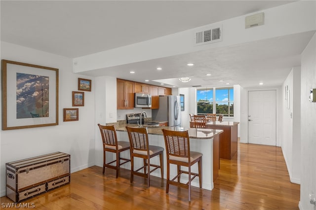 kitchen featuring kitchen peninsula, sink, a breakfast bar, and appliances with stainless steel finishes