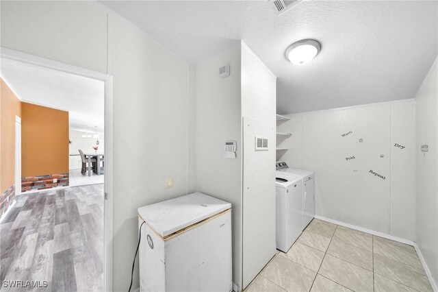 clothes washing area featuring light hardwood / wood-style floors, a textured ceiling, and independent washer and dryer