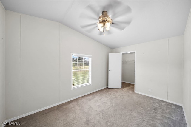 unfurnished bedroom featuring ceiling fan, light colored carpet, a walk in closet, vaulted ceiling, and a closet