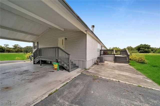 view of side of property featuring a yard, a deck, and central AC unit