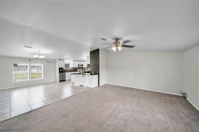 unfurnished living room featuring ceiling fan with notable chandelier and light colored carpet