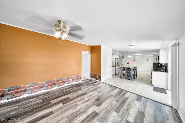 unfurnished living room with light wood-type flooring and ceiling fan