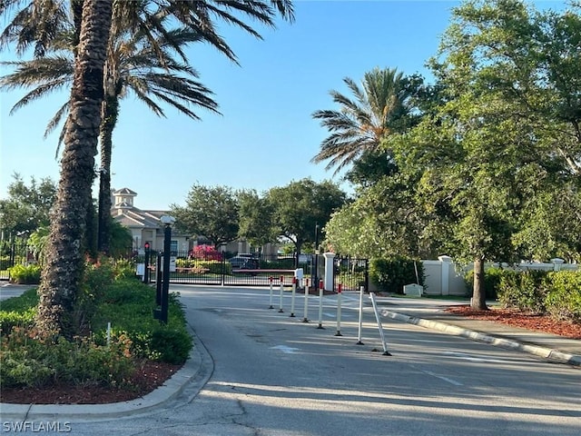 view of road with a gate, a gated entry, and curbs