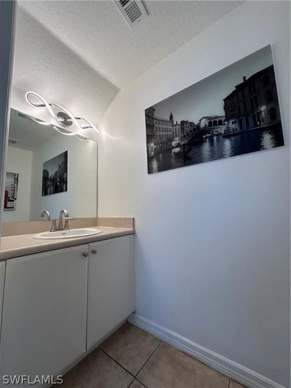 bathroom with visible vents, tile patterned flooring, vanity, baseboards, and a textured ceiling
