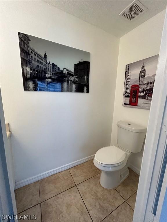 bathroom featuring toilet, baseboards, visible vents, and tile patterned floors