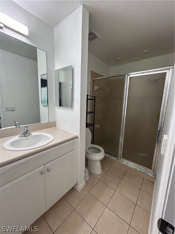 bathroom with tile floors, a shower with door, toilet, and large vanity