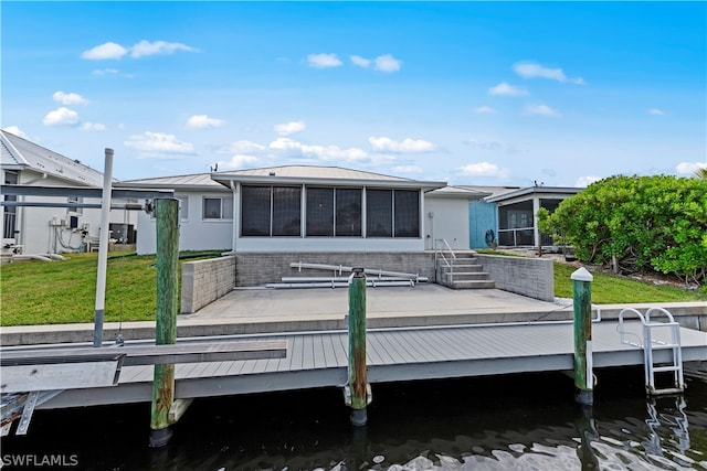 rear view of house with a water view, a lawn, and a sunroom