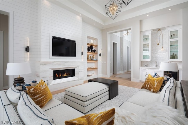 living room with a fireplace, an inviting chandelier, light hardwood / wood-style flooring, and sink