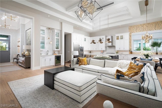 living room featuring a healthy amount of sunlight, sink, wine cooler, and light hardwood / wood-style flooring