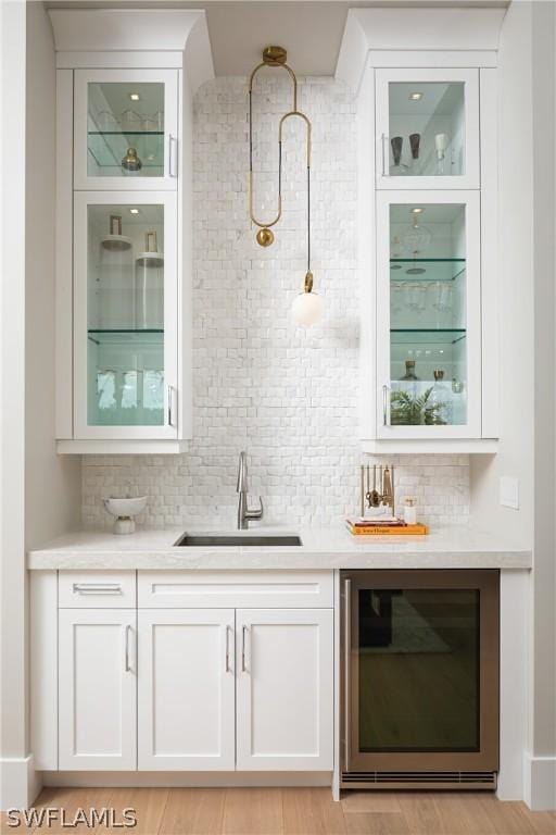 bar featuring wine cooler, white cabinetry, sink, and decorative backsplash