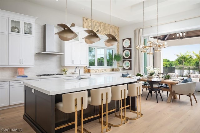 kitchen featuring white cabinets, wall chimney exhaust hood, sink, and tasteful backsplash