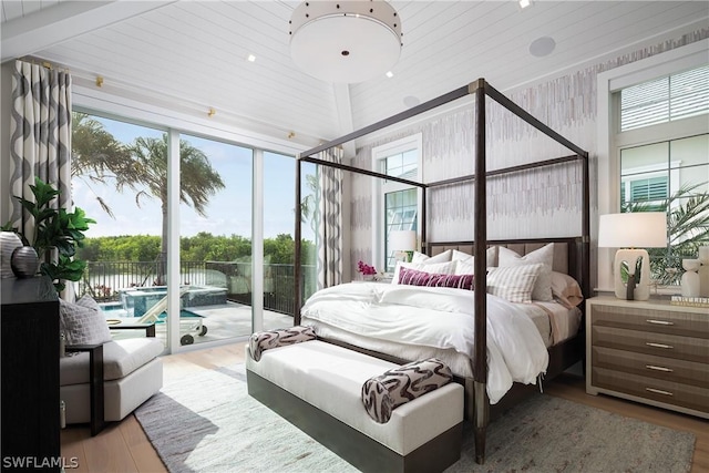 bedroom with access to outside, multiple windows, and hardwood / wood-style flooring