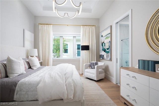 bedroom featuring a chandelier, a tray ceiling, and light hardwood / wood-style floors