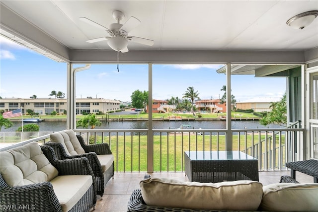 sunroom featuring ceiling fan and a water view