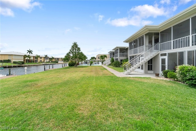 view of yard featuring a sunroom and a water view