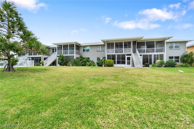 rear view of property featuring a lawn and a sunroom