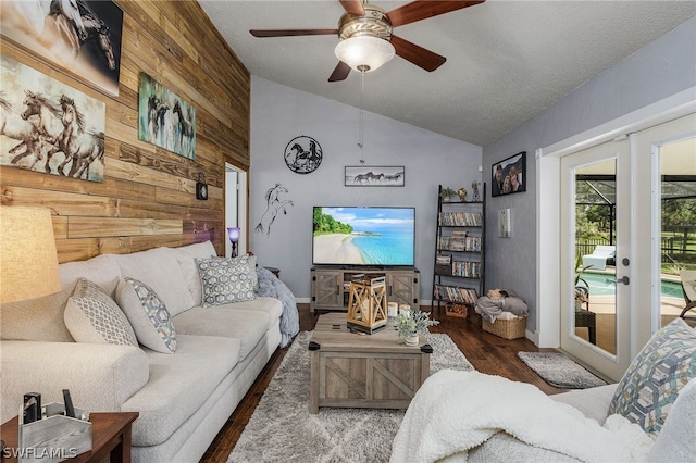 living room with ceiling fan, dark hardwood / wood-style floors, a textured ceiling, vaulted ceiling, and wooden walls