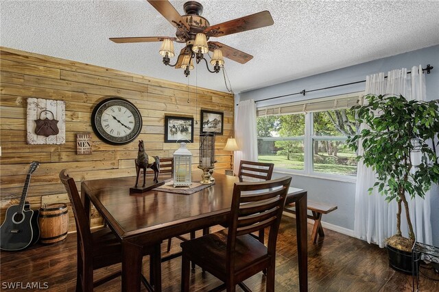 dining space with a textured ceiling, dark hardwood / wood-style floors, ceiling fan, and wooden walls