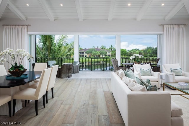 sunroom / solarium featuring beamed ceiling and a water view