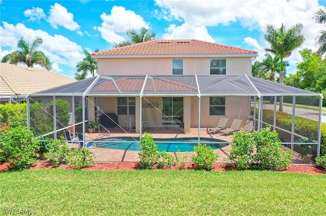 rear view of property featuring a yard, a patio, and glass enclosure