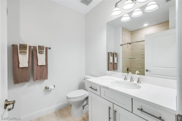 bathroom featuring hardwood / wood-style flooring, vanity, toilet, and a tile shower