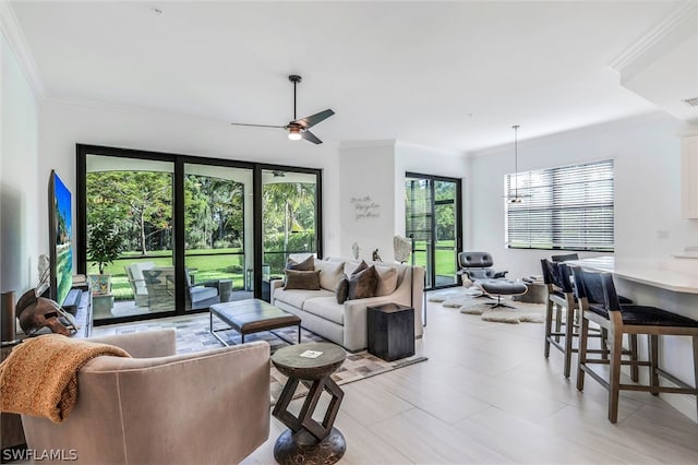 living room featuring plenty of natural light, ornamental molding, and ceiling fan with notable chandelier