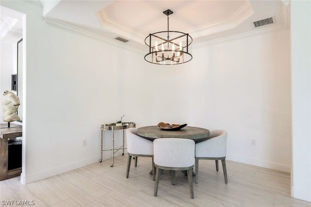 dining room featuring a chandelier, a raised ceiling, and ornamental molding