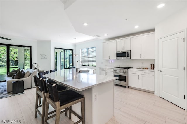 kitchen featuring appliances with stainless steel finishes, plenty of natural light, a kitchen breakfast bar, and a kitchen island with sink