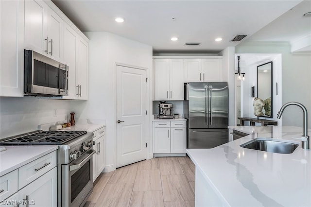 kitchen with white cabinetry, sink, ornamental molding, and premium appliances