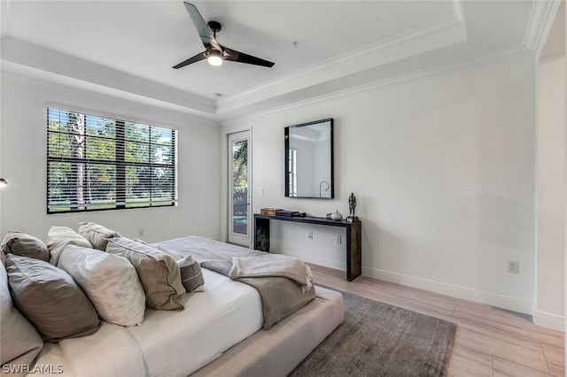 bedroom with ceiling fan, light hardwood / wood-style floors, a raised ceiling, and crown molding