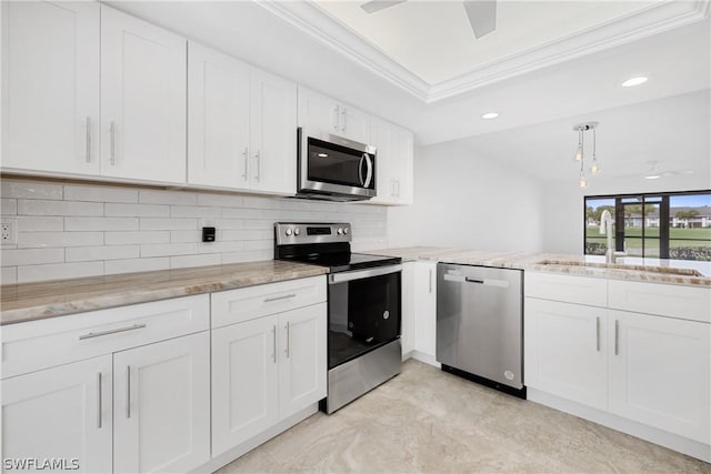 kitchen featuring sink, crown molding, appliances with stainless steel finishes, white cabinetry, and a tray ceiling