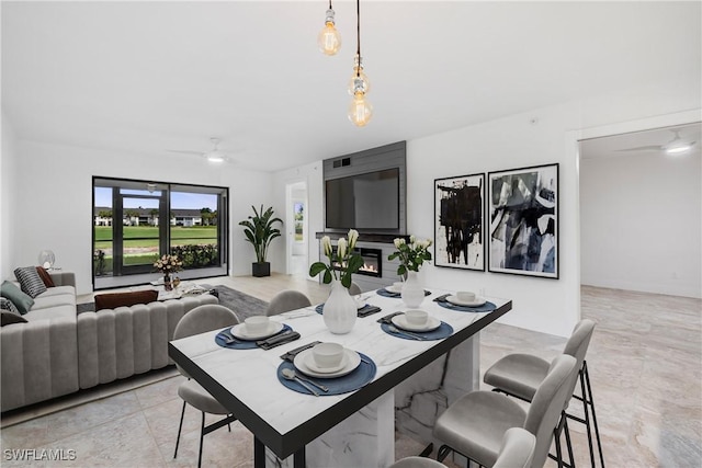 dining area with ceiling fan and a fireplace