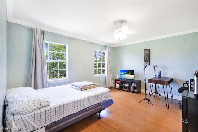 bedroom with hardwood / wood-style floors, ceiling fan, and crown molding