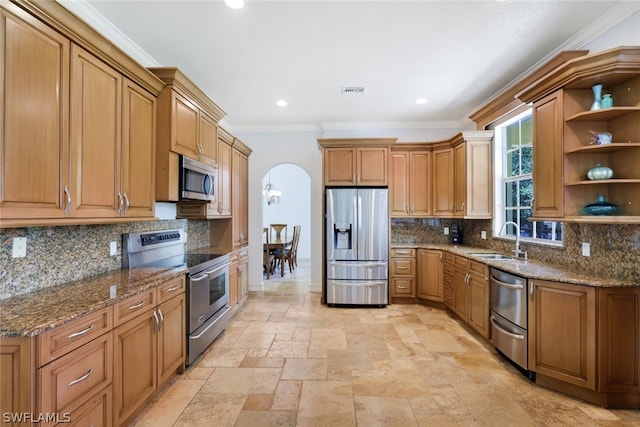 kitchen with stone counters, appliances with stainless steel finishes, ornamental molding, and sink