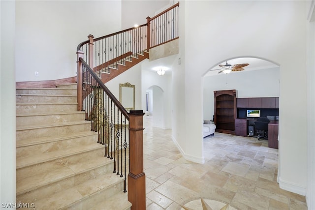 staircase with ceiling fan, a towering ceiling, and crown molding