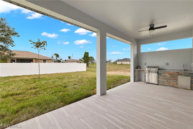 wooden terrace featuring ceiling fan, area for grilling, a patio, grilling area, and a yard