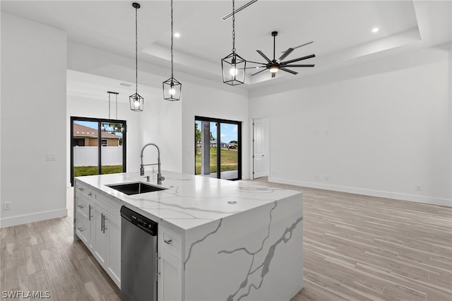 kitchen with a raised ceiling, dishwasher, decorative light fixtures, and sink