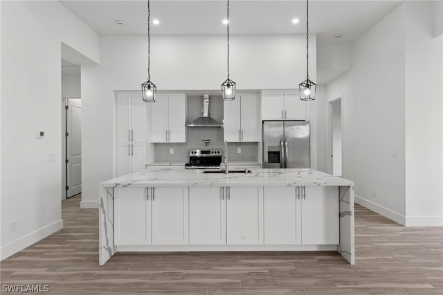 kitchen featuring wall chimney exhaust hood, stainless steel fridge, pendant lighting, and stove