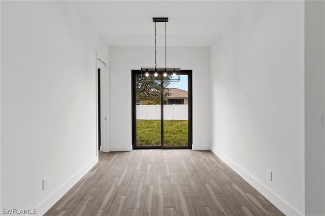 unfurnished dining area featuring light hardwood / wood-style floors and a chandelier