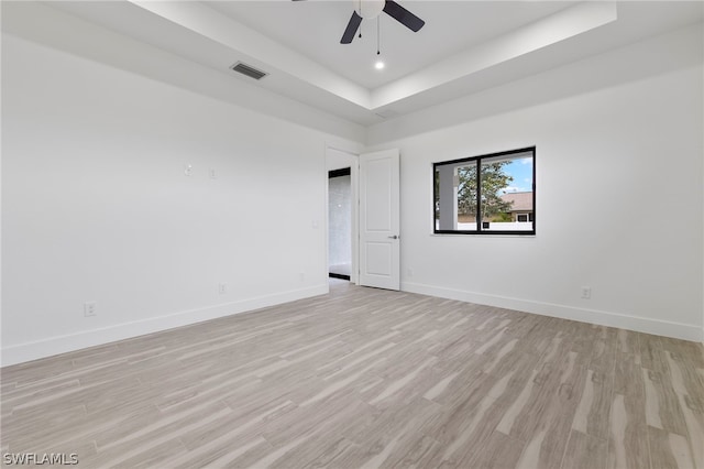 empty room featuring ceiling fan, a raised ceiling, and light hardwood / wood-style flooring