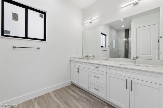 bathroom with a shower with shower door, dual bowl vanity, and hardwood / wood-style flooring