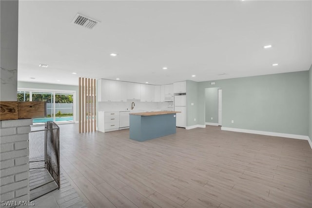 kitchen featuring white appliances, white cabinetry, light wood-type flooring, sink, and butcher block countertops