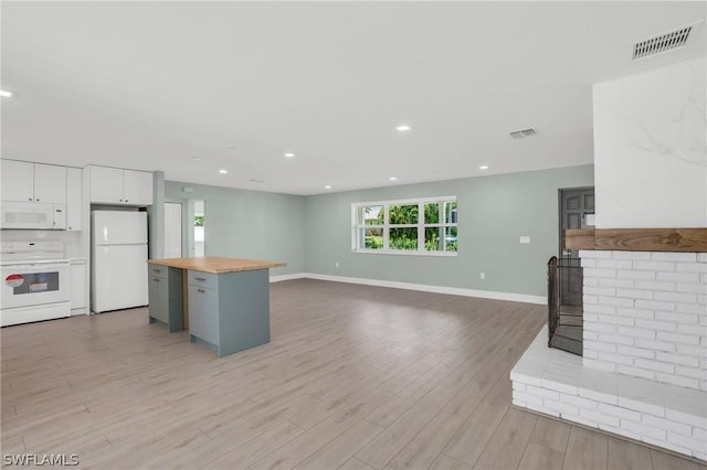 kitchen with light wood-type flooring, white cabinetry, white appliances, a center island, and wood counters