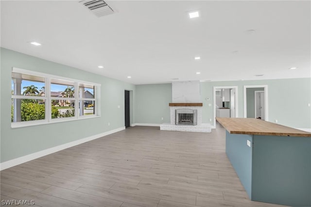 unfurnished living room with a fireplace and light wood-type flooring