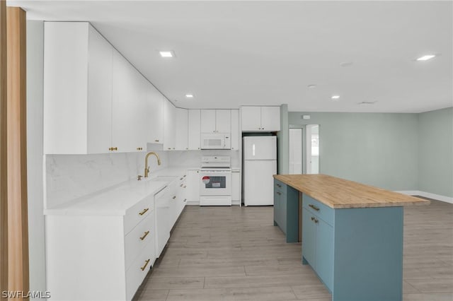 kitchen with sink, white cabinetry, white appliances, a kitchen island, and decorative backsplash