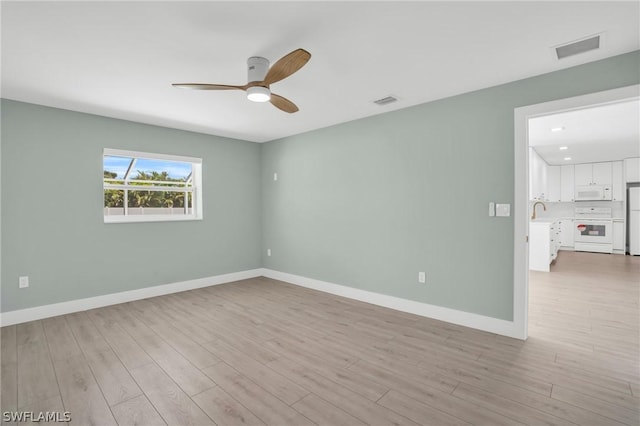 empty room featuring sink, ceiling fan, and light hardwood / wood-style flooring