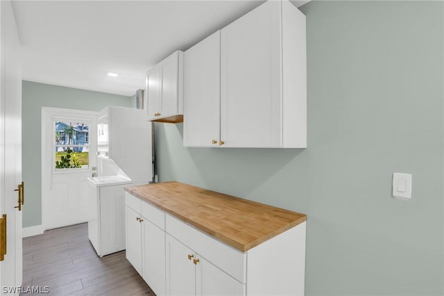 clothes washing area featuring light hardwood / wood-style floors and cabinets